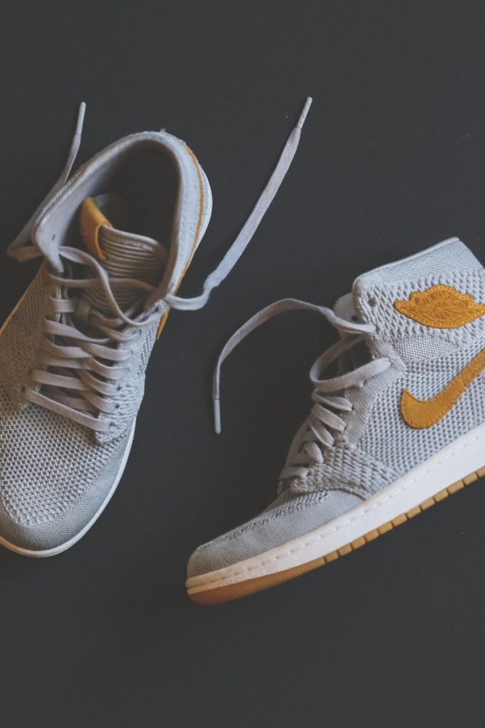 Close-up of fashionable gray and orange high-top sneakers displayed against a minimal background.